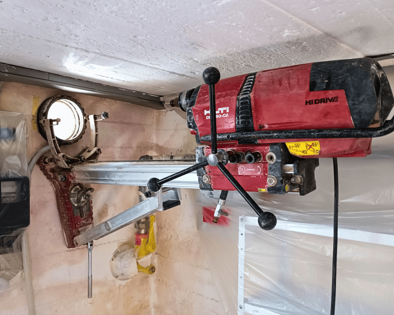 Rote Hilti Kernbohrmaschine bohrt ein Loch in eine Decke