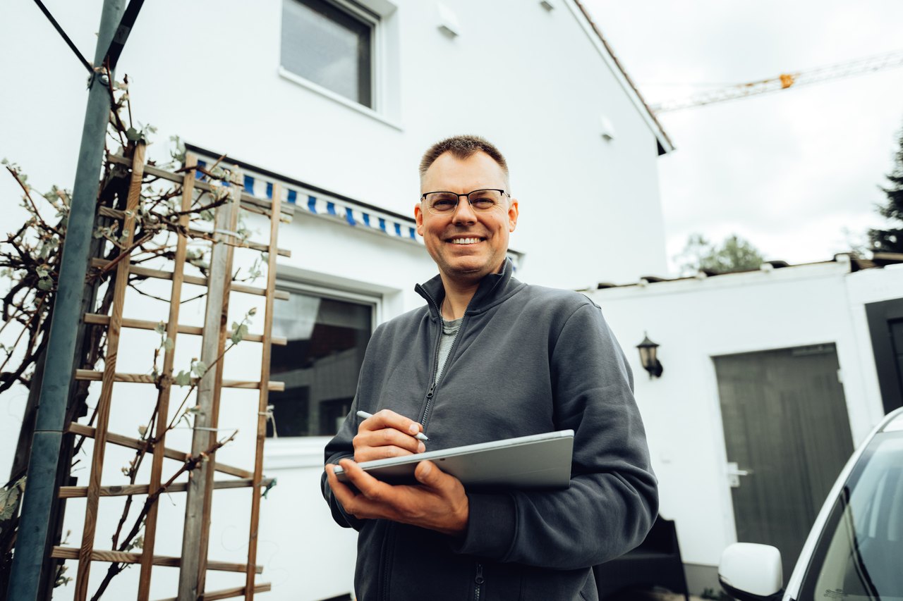 Fachmann mit Tablet vor einem Haus
